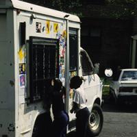 Two children line up outside ice cream truck in a vintage photograph.