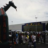 A crowd of people stand in a Toys R Us parking lot in a vintage photograph.